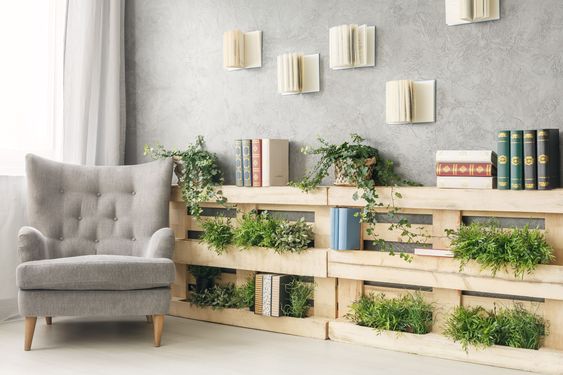 livres et plantes vertes rangés dans une bibliothèque murale en bois de palettes