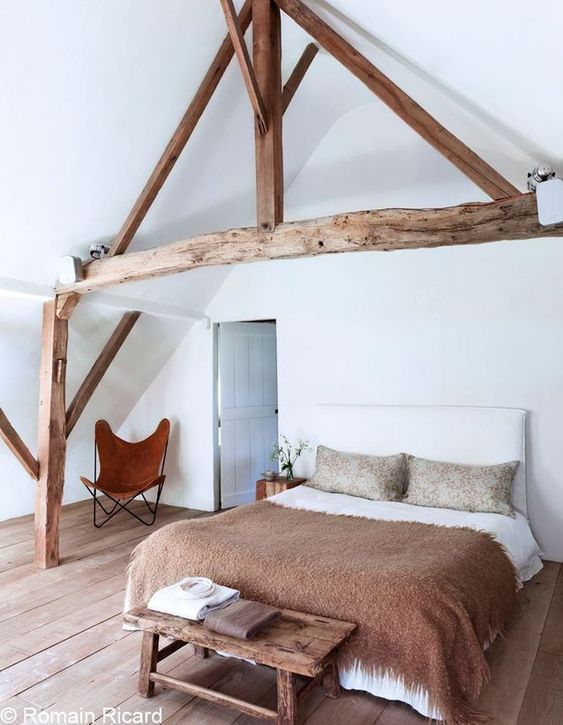 poutres en bois apparentes au dessus d'un lit dans une suite parentale au style rustique