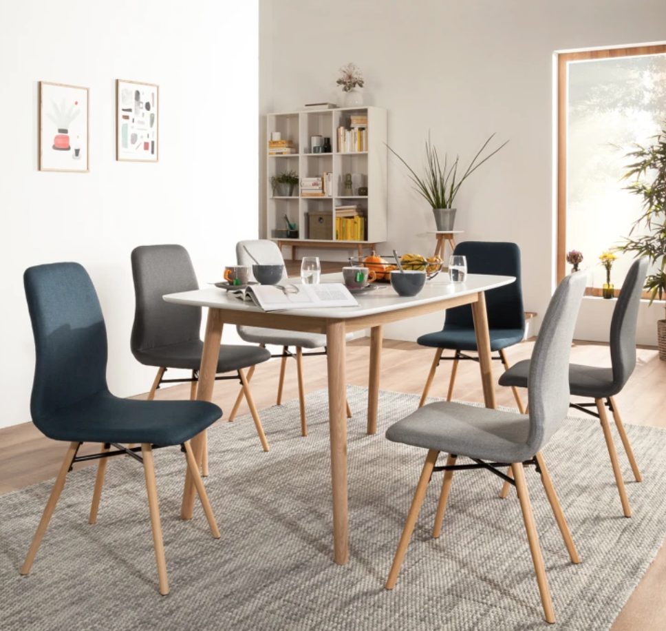 chaises dépareillées grises et bleues autour d'une table à manger rectangulaire