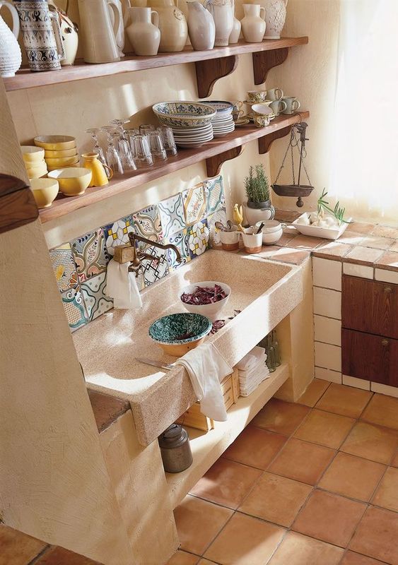 cuisine méditerranéenne avec évier en pierre et vaisselle en céramique rangée sur des étagères en bois