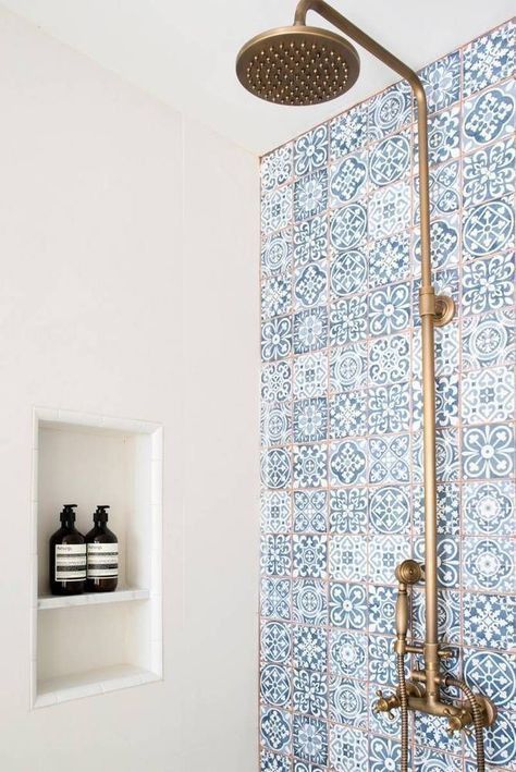 carreaux en zellige bleu derrière une douche italienne avec robinetterie en cuivre