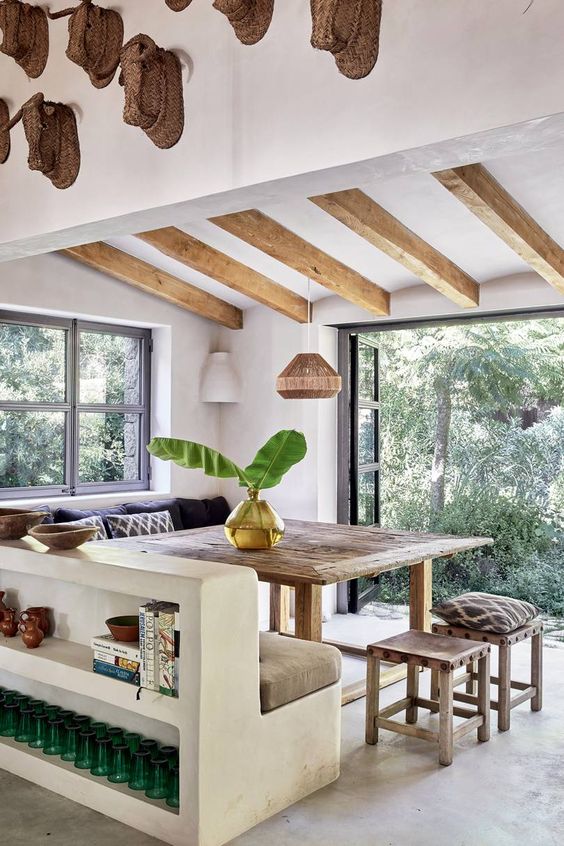 salle à manger dans une maison méditerranéenne avec sol en béton ciré et poutres apparentes au dessus d'une grande table en bois brut