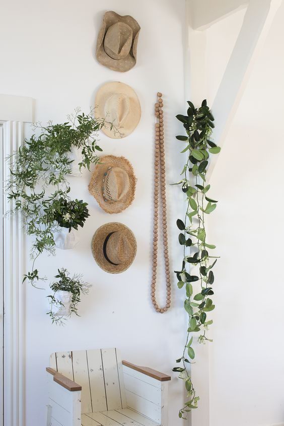 chapeaux de paille et plantes vertes accrochés à un mur blanc