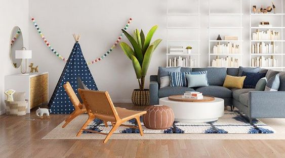 canapé d'angle bleu dans un salon en L avec un tipi et un espace de jeu pour enfants