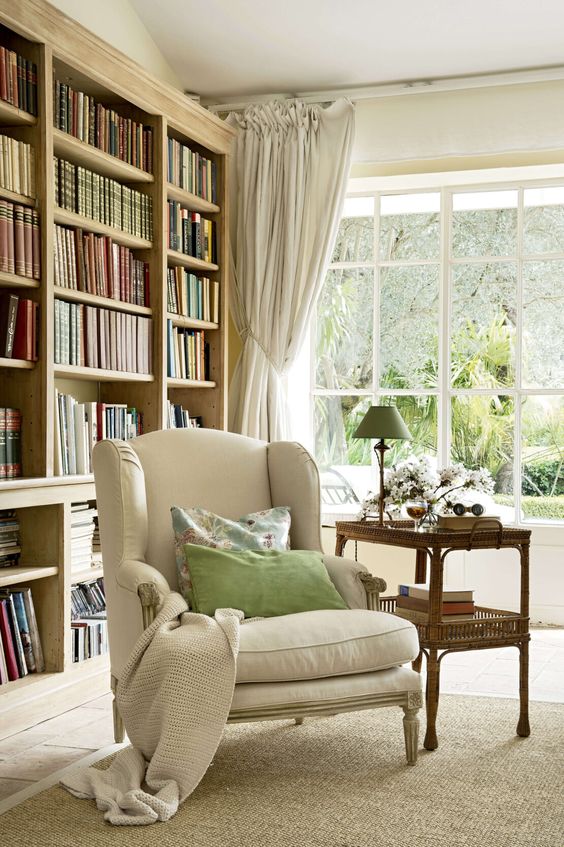 fauteuil classique confortable dans une grand pièce aux tons beiges avec bibliothèque en bois