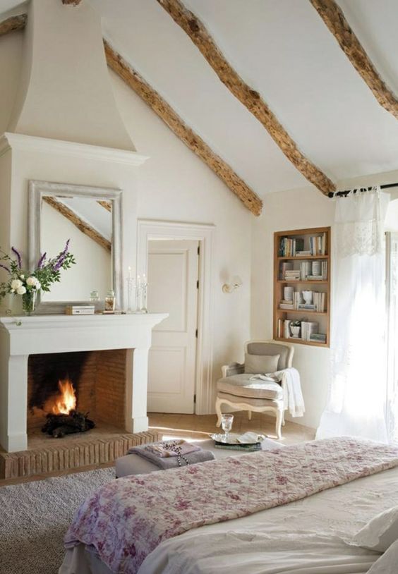 déco romantique dans une chambre blanche style cottage avec poutres apparentes et feu de cheminée