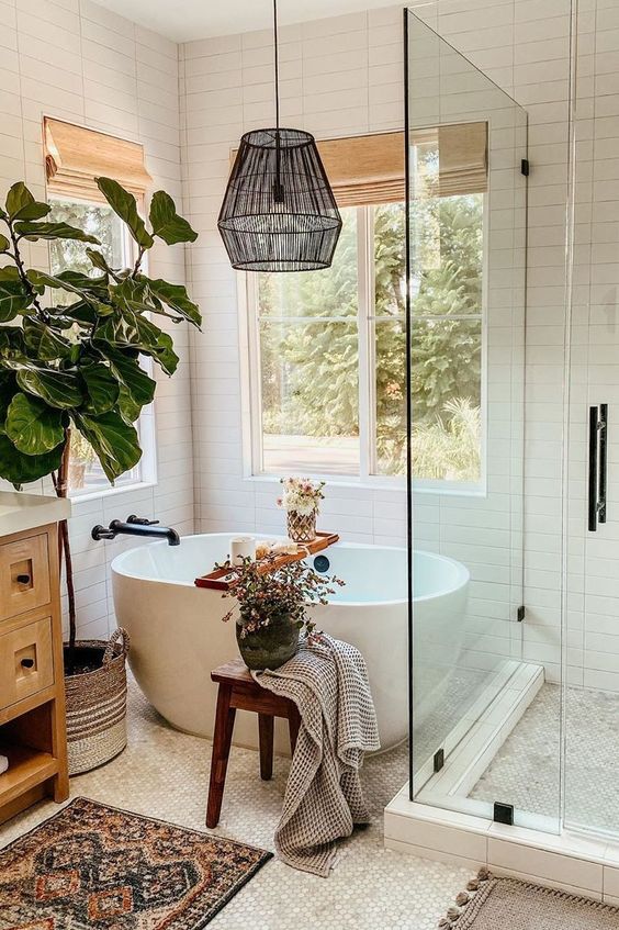 petite baignoire en céramique dans une salle de bains au style bohème avec tapis au sol et grande plante verte