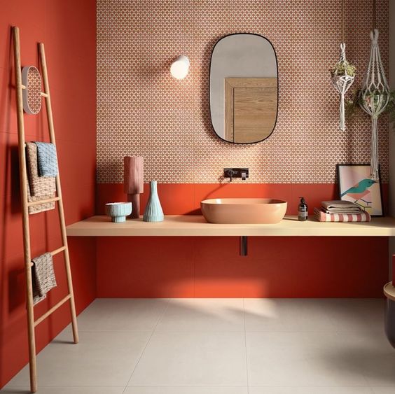 murs oranges avec papier peint derrière le miroir d'une salle de bains chic et colorée
