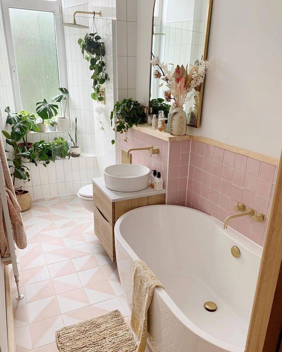 petite baignoire en céramique blanc dans une salle de bains rose décorée de plantes vertes