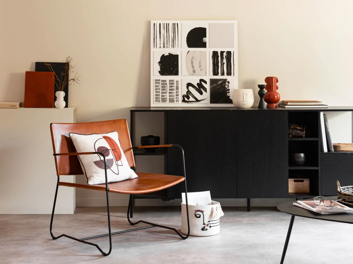 Un fauteuil arty en métal noir et cuir, à côté d'un meuble en bois