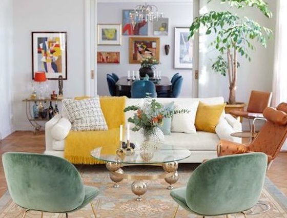 Salon très coloré, avec des cadres, un canapé, des coussins, des fauteuils et un tapis