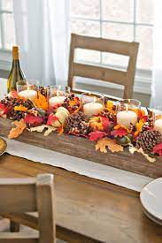 Déco de table automnale élaborée avec des bougies et des pommes de pin