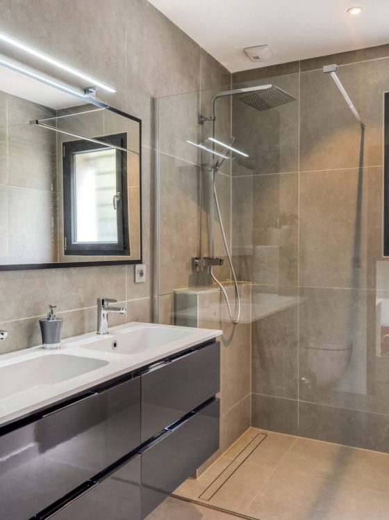 Une grande douche à l'italienne dans une salle d'eau à la déco moderne