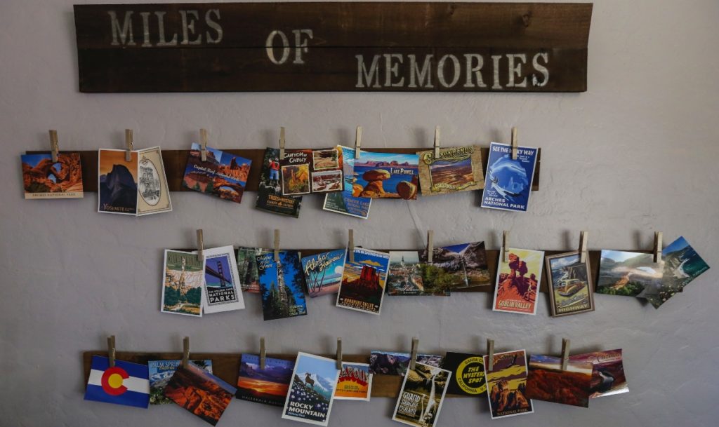 Des cartes postales, souvenirs de voyage, accrochées sur le mur, sur trois lignes