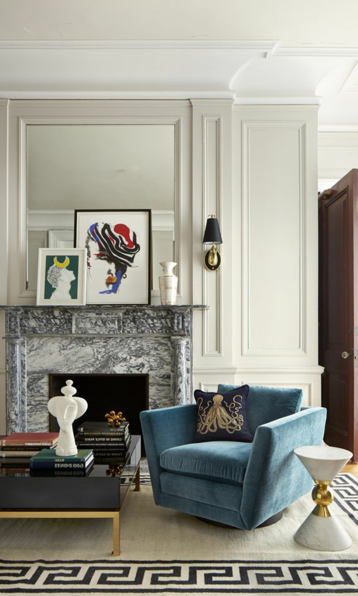 Un aménagement cheminée arty, avec un foyer surplombé par des tableaux colorés et un canapé en velours bleu