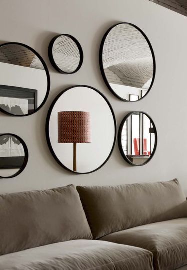 Le canapé est surplombé par des miroirs ronds, avec une bordure noire, de différents diamètres