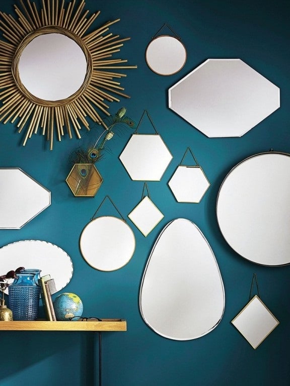 Le mur bleu canard est décoré avec des miroirs ronds ou de formes géométriques