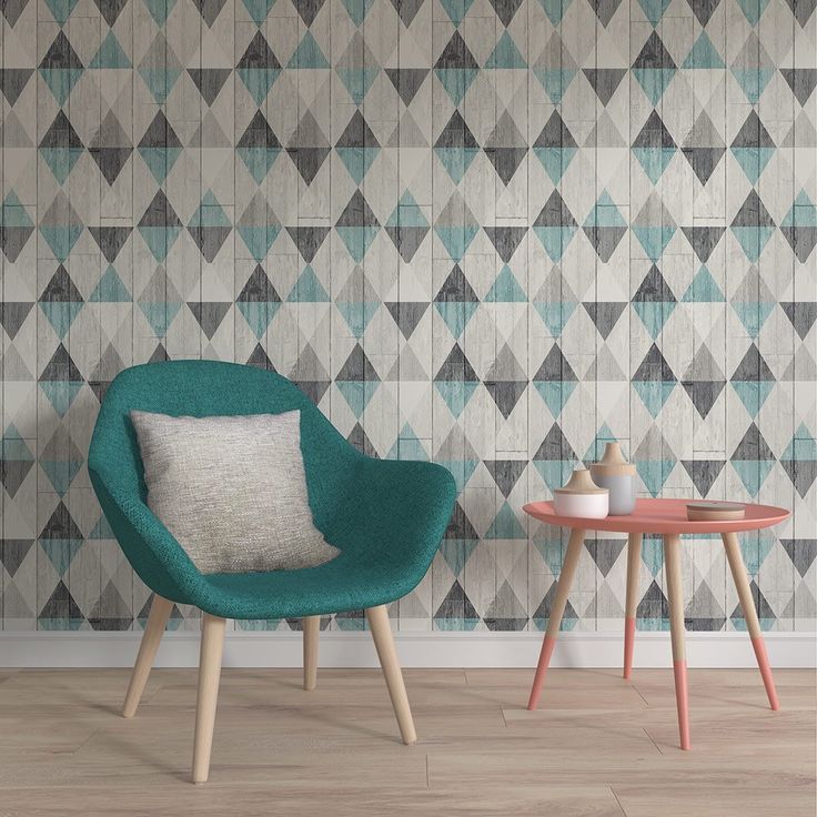 Un fauteuil et une petite table de style scandinave devant un mur recouvert de papier peint à motifs géométriques