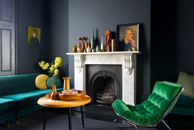 La cheminée claire contraster avec le mur noir, tandis que le fauteuil et le canapé turquoise ajoutent une touche de peps