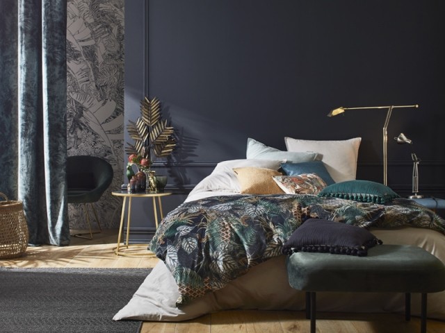 Grande chambre exotique, avec du gris et du bleu sur les murs, le lit et les rideaux