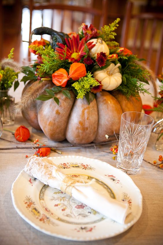 Une déco Thanksgiving faite avec une citrouille creusée en forme de vase, dans laquelle s'épanouissent quelques fleurs