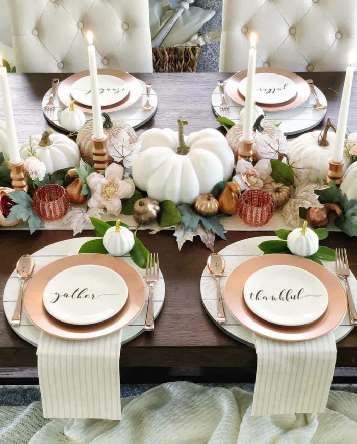 La table est décorée de manière élégante, avec des citrouilles blanches et de grands cierges blancs