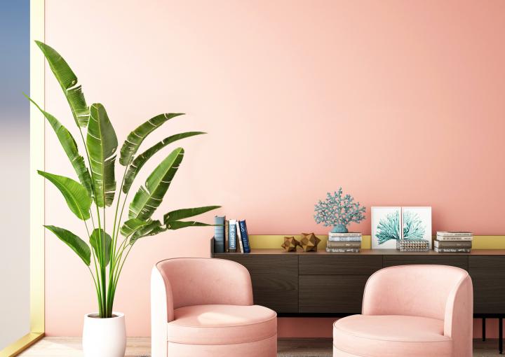 Cette chambre exotique se pare de coloris pastel, avec un mur et deux fauteuils rose poudré