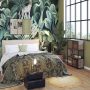 Le lit deux places se pare de draps aux motifs végétaux, avec un sol en parquet et du papier peint tropical au-dessus de la tête de lit