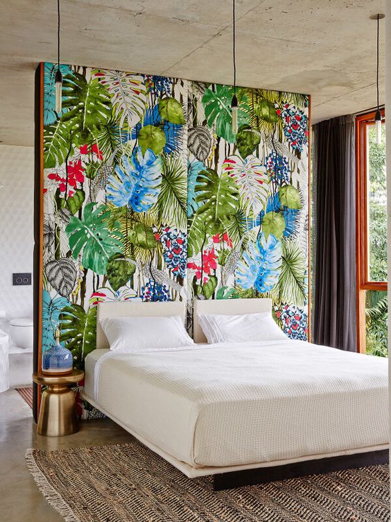 Un papier peint tropical, avec des couleurs chatoyantes, surplombe le lit deux places aux draps blancs