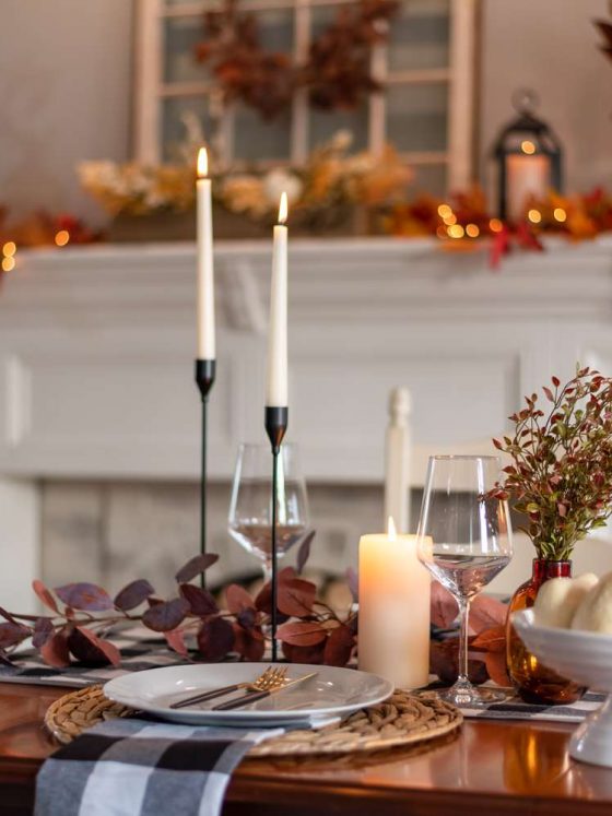 Une table avec de la déco Thanksgiving réalisée avec des bouquets de feuilles séchées et des bougies
