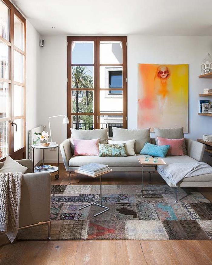 Une pièce de vie lumineuse avec un mobilier typique des tendances déco 2023, et un tapis en patchwork