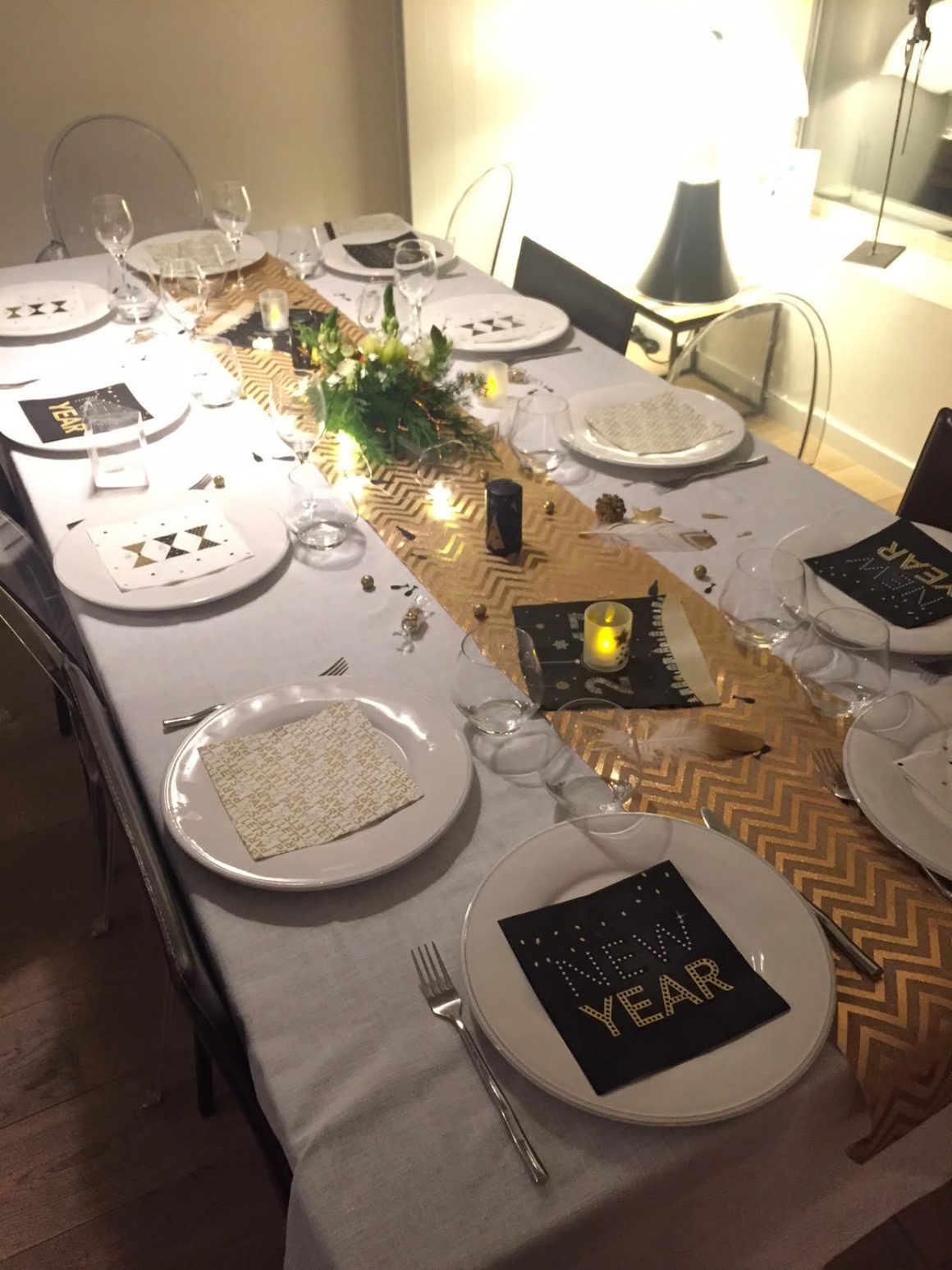 Un chemin de table dorée orne une nappe blanche, avec d'élégantes assiettes de style minimaliste