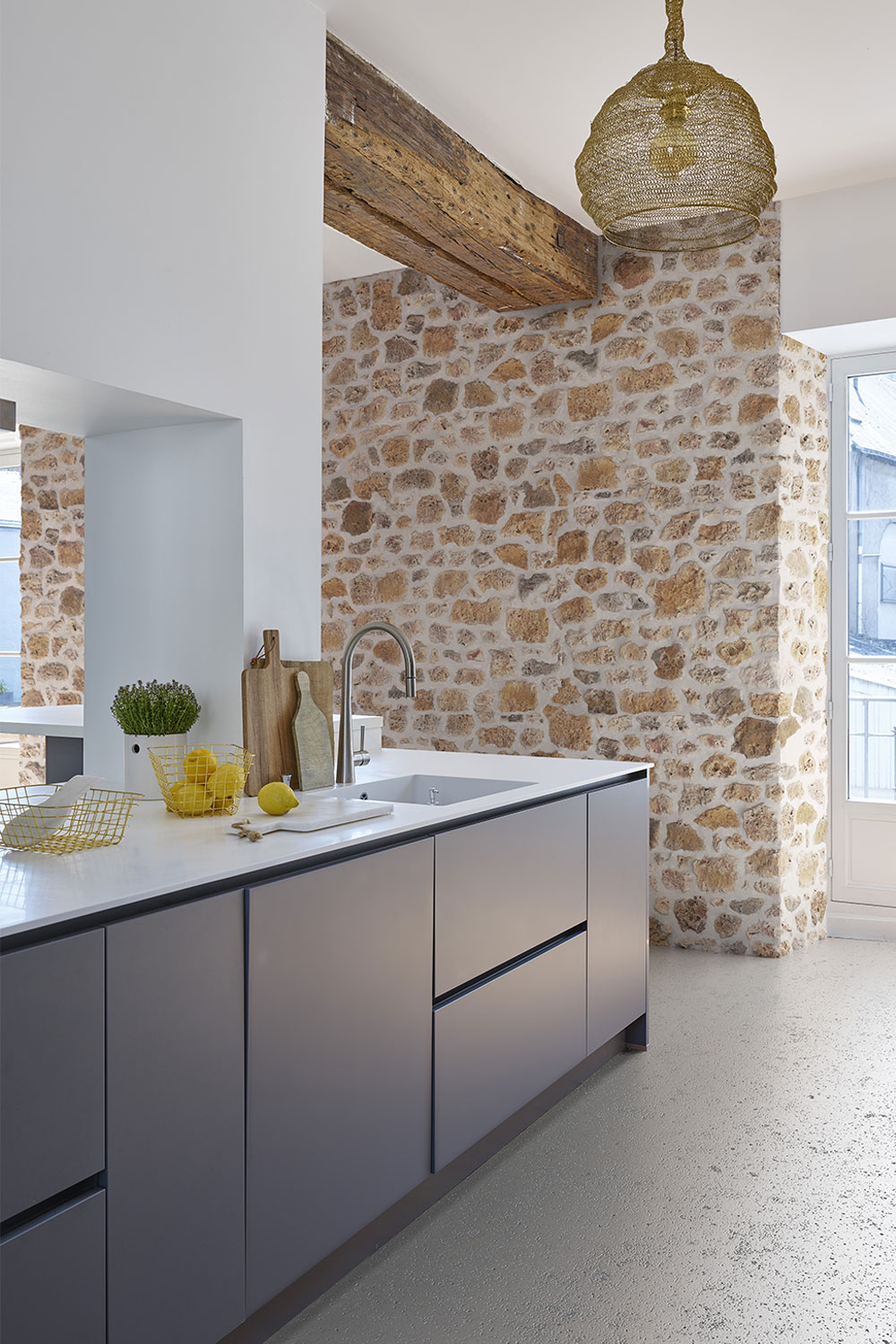On remarque un élégant contraste entre le mur en brique et le mur plus lisse de la cuisine. Poutres apparentes au plafond.