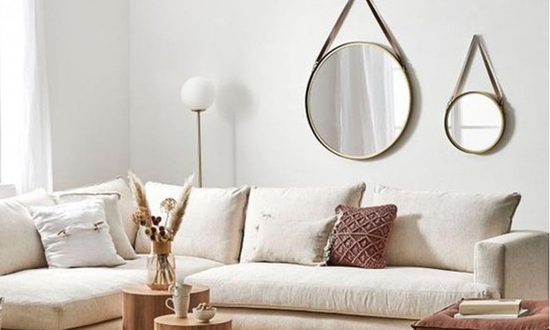 Un miroir rond, au-dessus d'un canapé de style scandinave