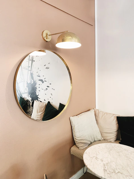 Un miroir rond avec des bords cuivrés qui sublime un mur dans les tons crème