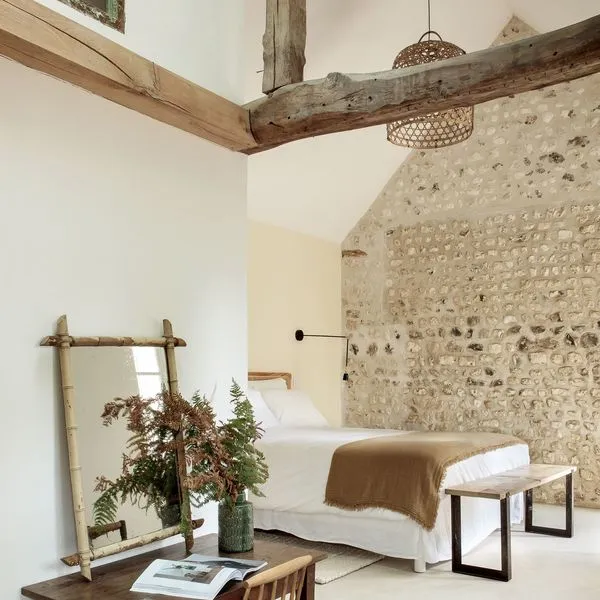 Des différences de texture pour aménager un espace ouvert, avec un mur en pierre dans le salon et un mur lisse au premier plan