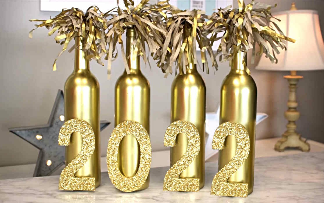 Quatre bouteilles de vin, vides, bombées en doré, avec les chiffres de la nouvelle année