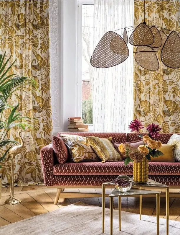 Le canapé aux motifs graphiques se marient à merveille avec les rideaux ornés de feuilles tropicales