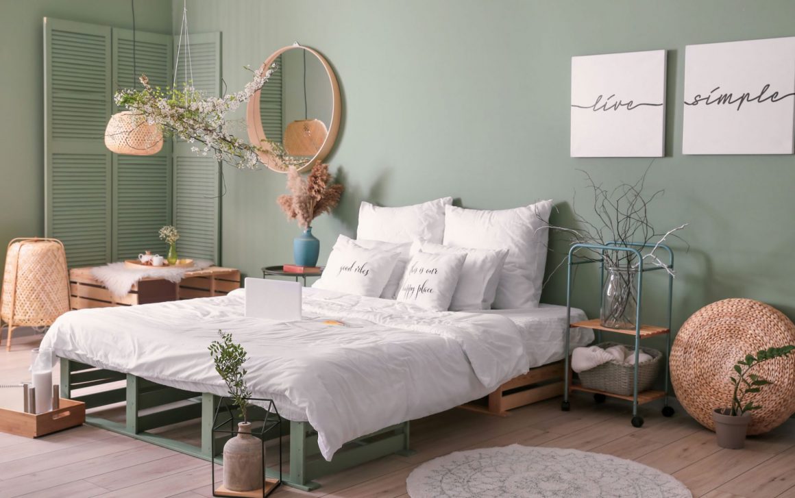 Une déco chambre tendance avec des murs vert amande, un lit blanc et des accessoires en osier
