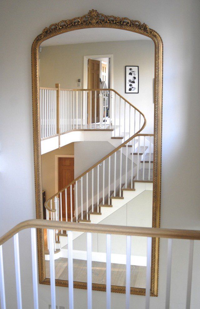 Un grand miroir met en valeur un escalier blanc et bois