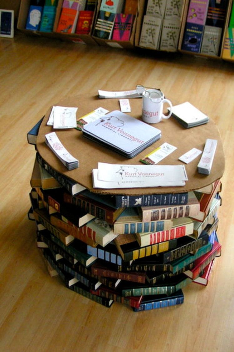 La table est de forme ronde, avec un plateau en bois et un empilement de livres