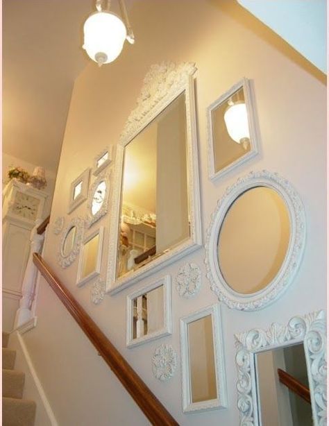 Des miroirs de style baroque, repeints en blanc, ornent le mur de cette montée d'escalier
