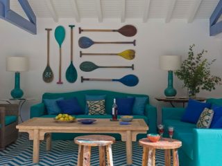 Aménagement pool house dans une ambiance de bord de mer, avec du bois flotté, du bleu, et des pagaies accrochées au mur