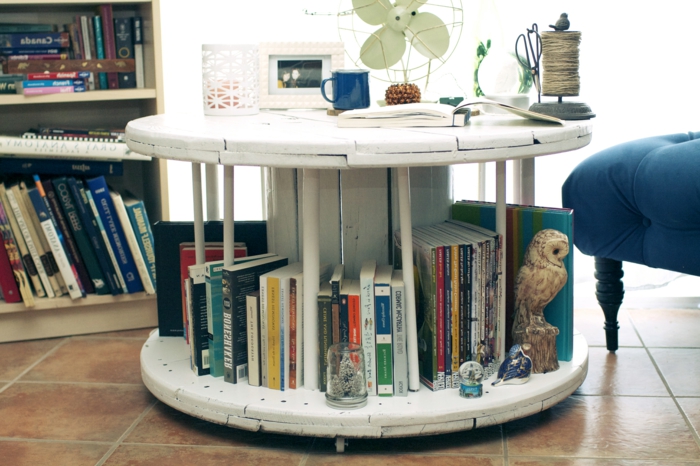 Ce touret bibliothèque et table basse accueille des livres. Il est monté sur roulettes et peint en blanc.