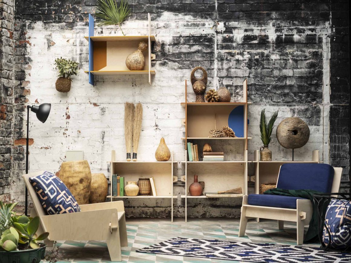 Une pièce de vie dans le style africain, avec des fauteuils en bois, des coussins bleus et des objets artisanaux dans la bibliothèque