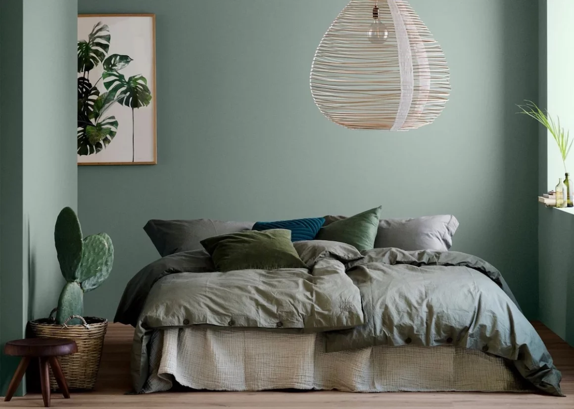Cette chambre parentale arbore des nuances de vert amande, sur le lit et sur les murs