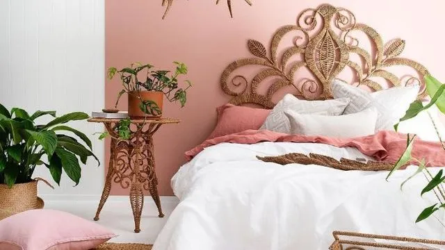 La chambre parentale comprend un grand lit aux coussins roses, devant un mur rose pâle
