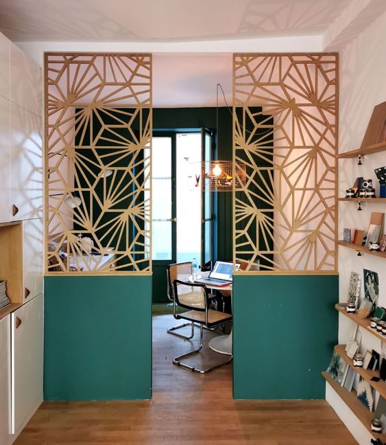 Un claustra en bois découpé avec des formes géométriques, et peint en doré et en vert