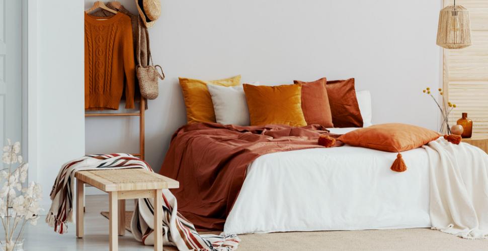Des couleurs du printemps dans la chambre, avec des coussins et un plaid terracotta sur le lit deux places