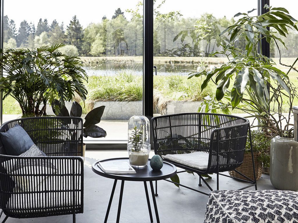 Ce jardin d'hiver contemporain accueille du mobilier en rotin noir